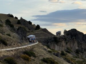A large truck is driving down a steep hill during sunset