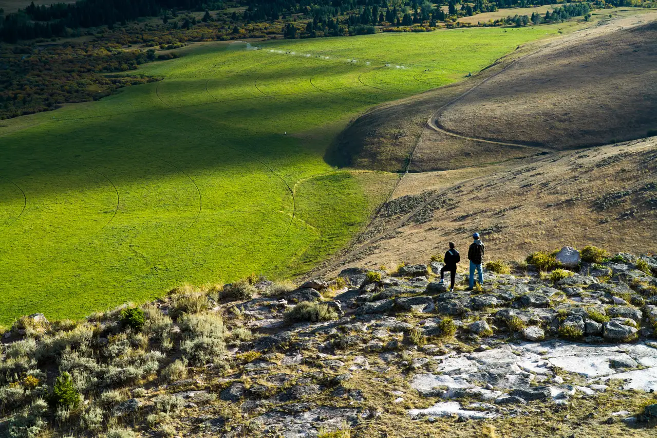 Three people on a hill overlooking a valley