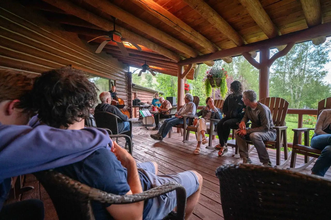 A group of people gathered on a deck, playing music and socializing