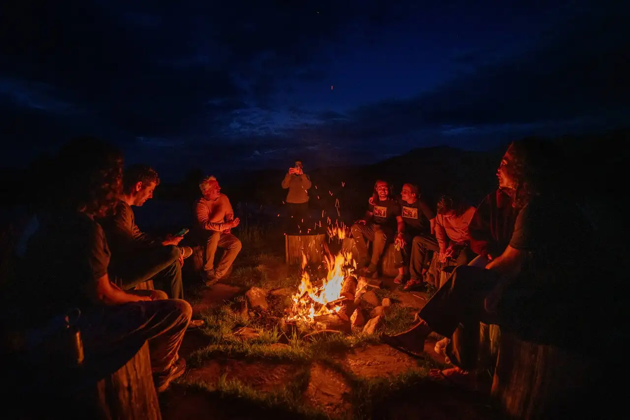 A group of people sitting around a fire at night