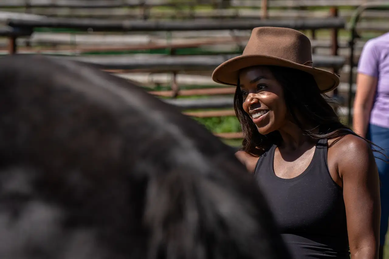 A woman in a brown hat standing next to a horse