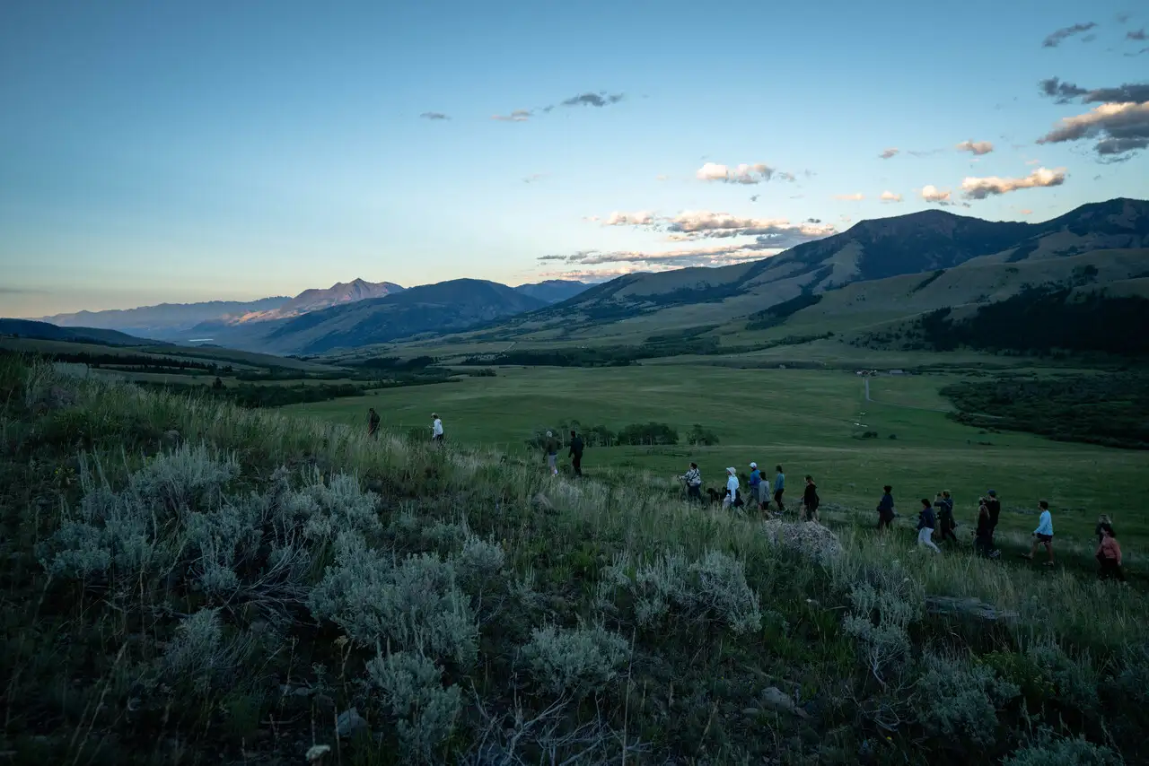 People walking in a field with mountains in the background