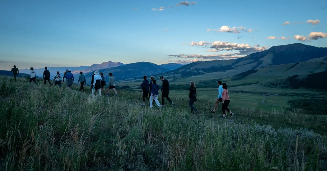 A group of people walking up a hill in a field