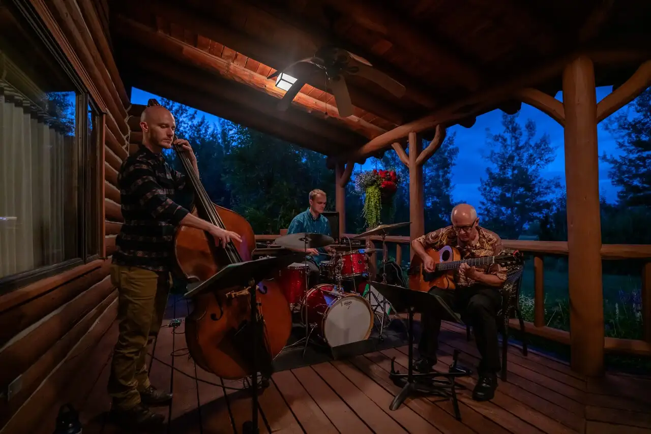 Three men playing instruments on a wooden deck at night