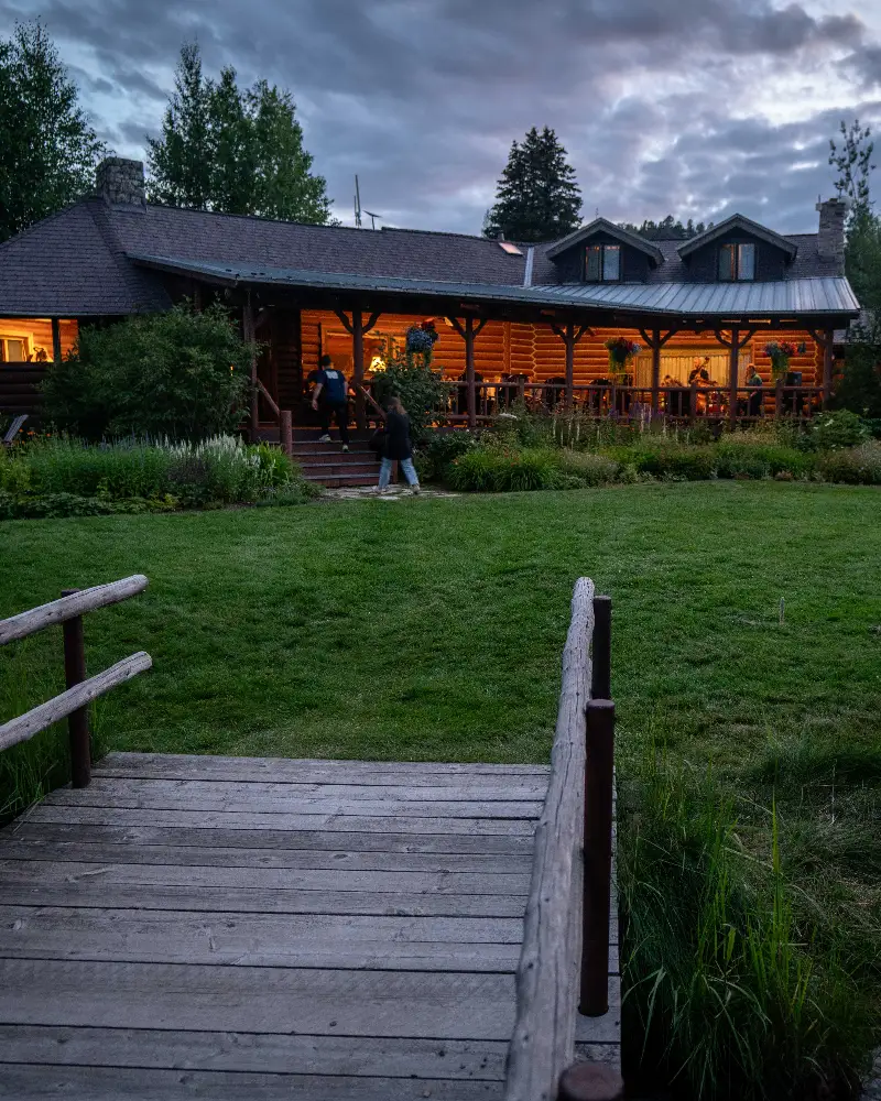 A wooden deck with a railing overlooking a grassy area with a building in the background