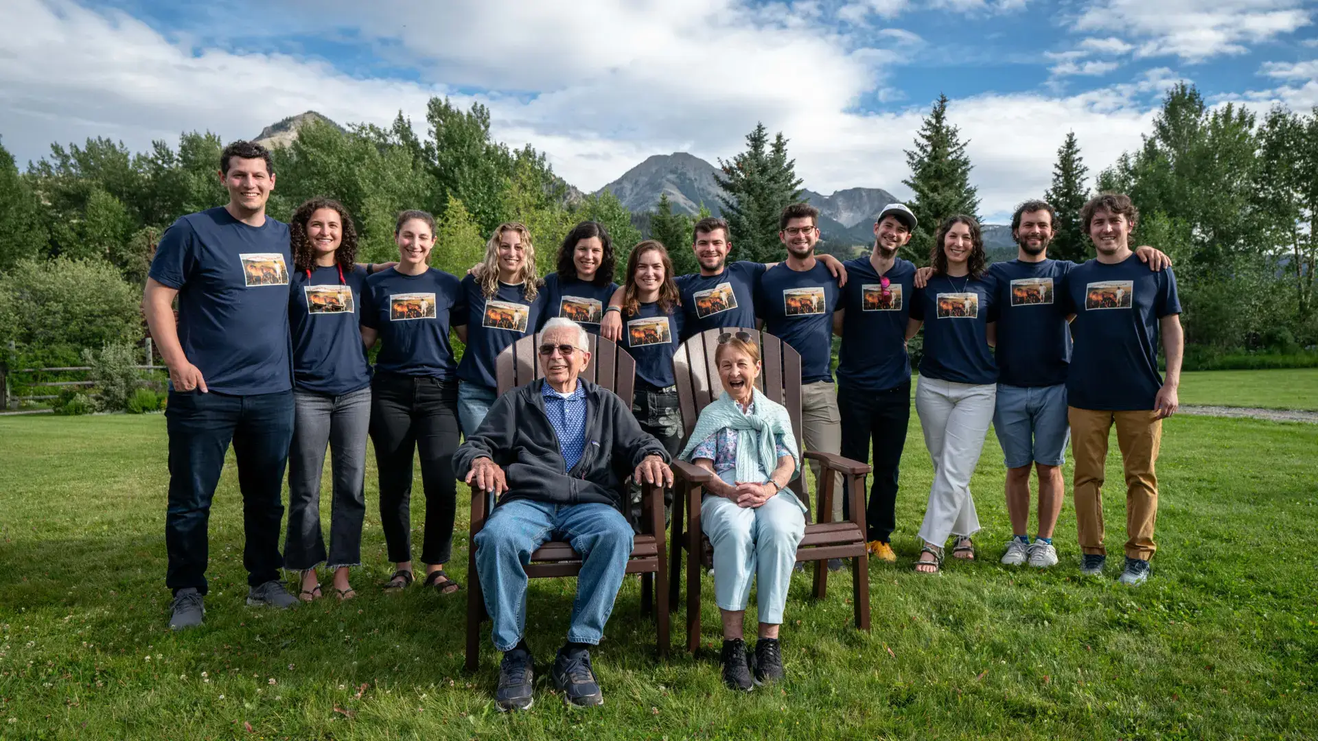 A group of people sitting on chairs in a grassy field