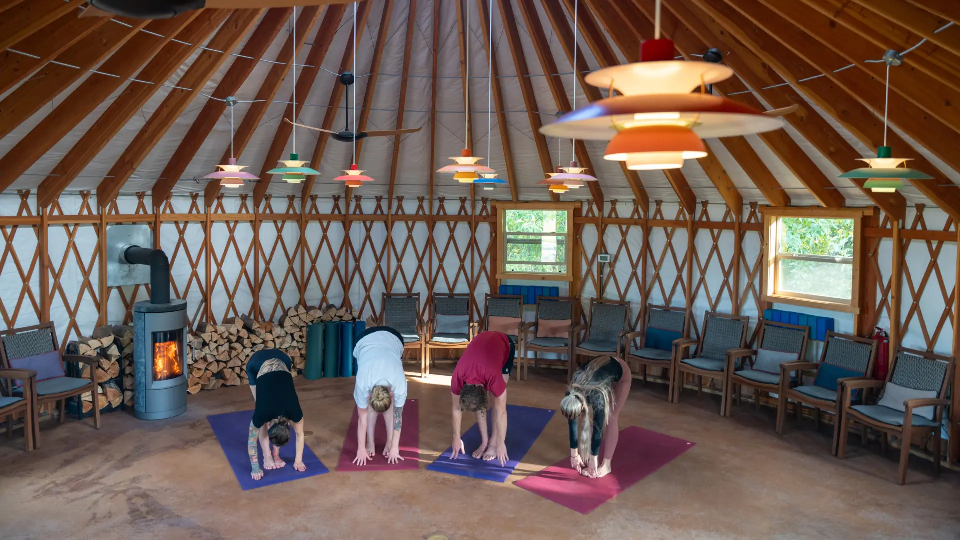 A group of people doing yoga in a room with colorful lights and umbrellas hanging from the ceiling