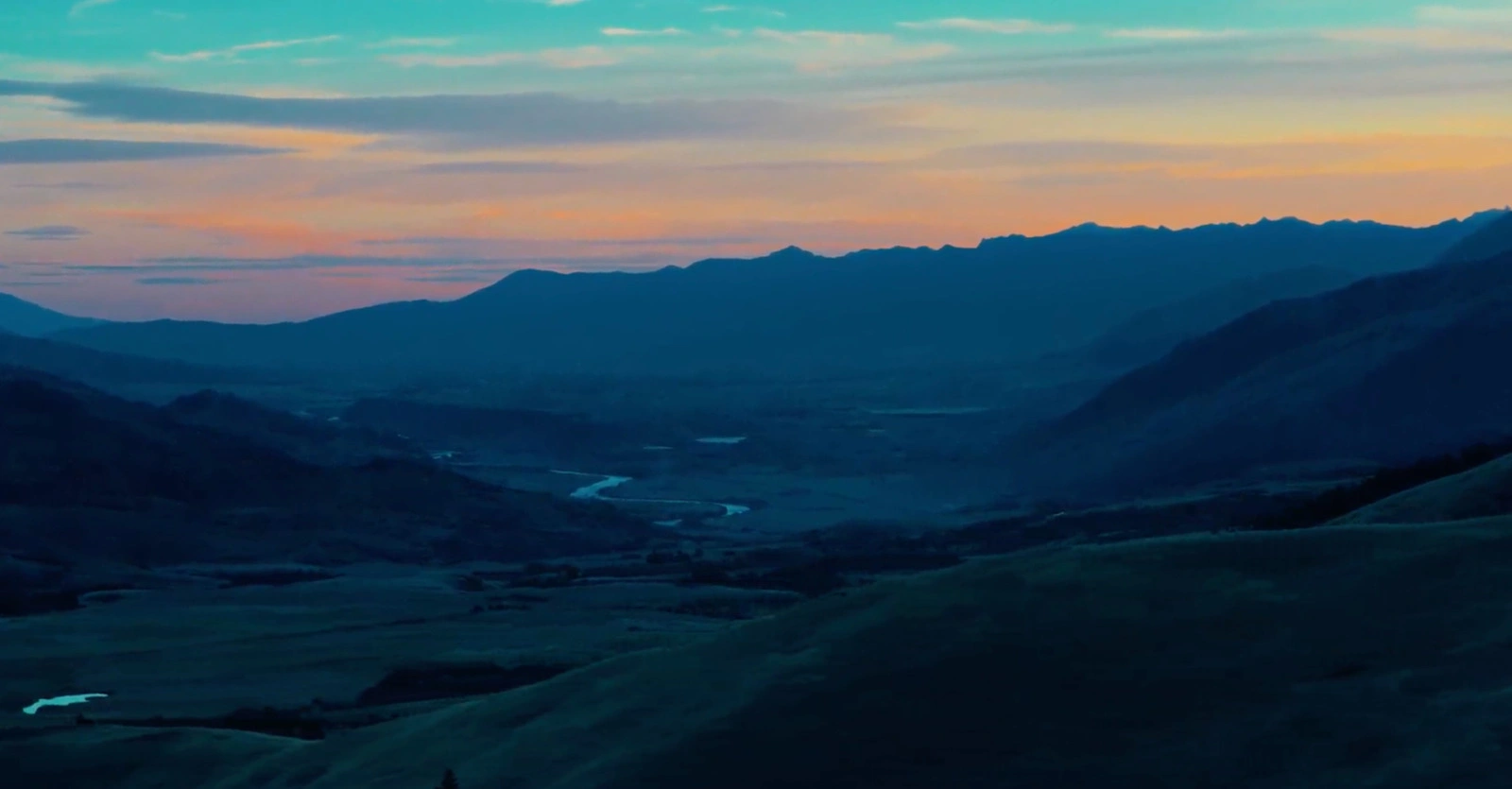 A valley with mountains and trees during sunset