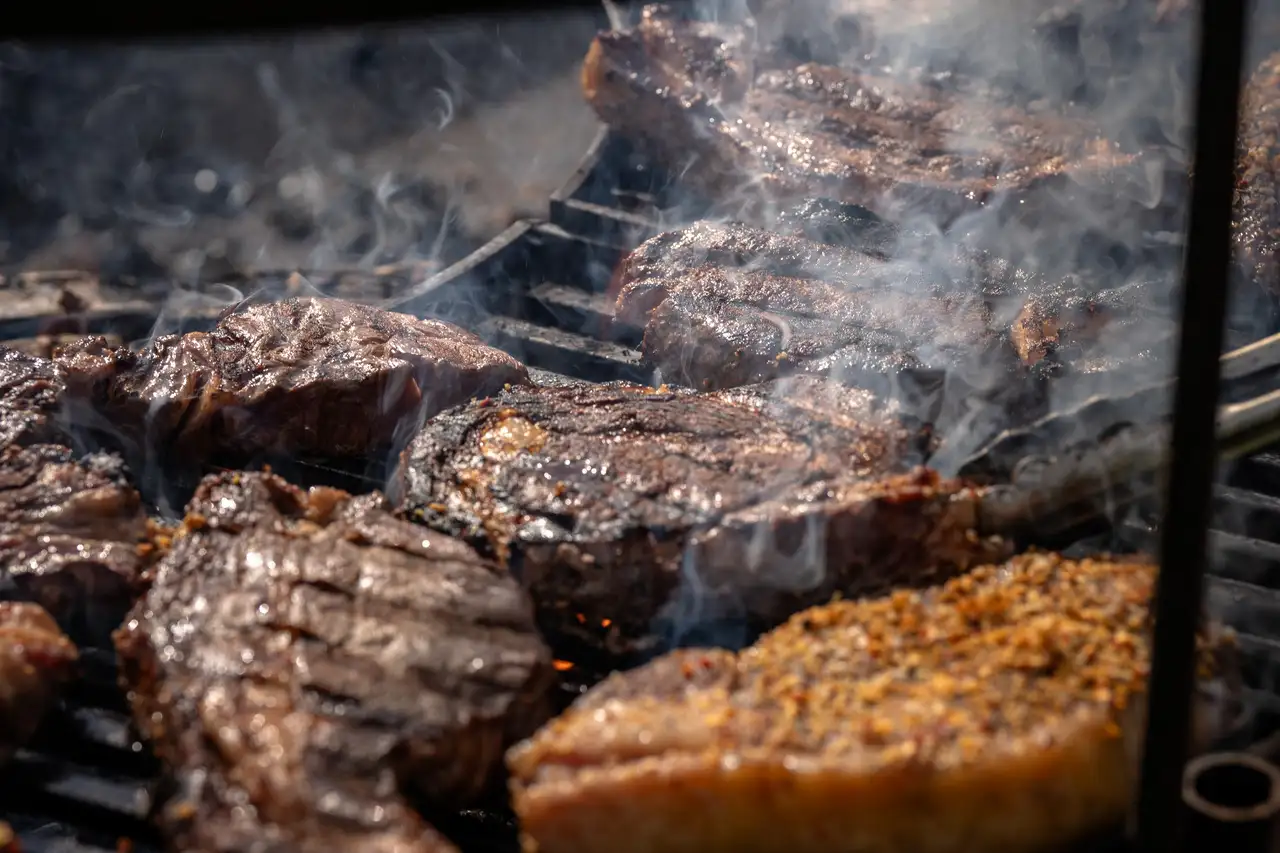 A grill with various pieces of meat cooking on it