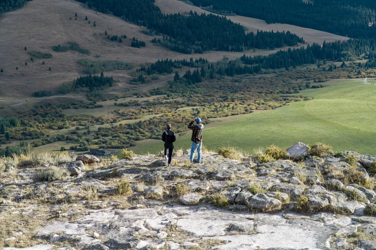 Two people on a rocky hilltop taking pictures