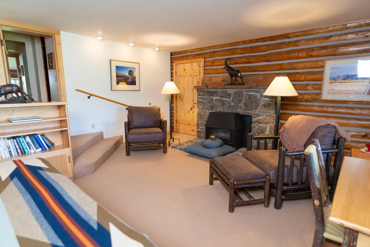 A cozy living room with a fireplace and wooden walls