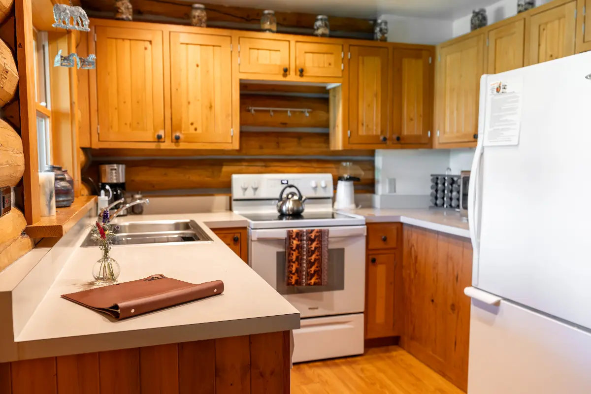 A kitchen with a white stove top oven, wooden cabinets, and a brown purse on the countertop