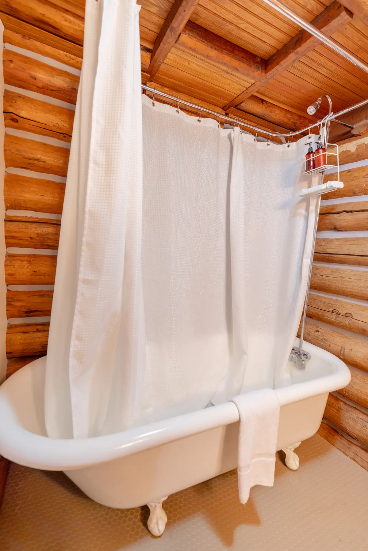 A white shower curtain hangs over a white bathtub in a bathroom