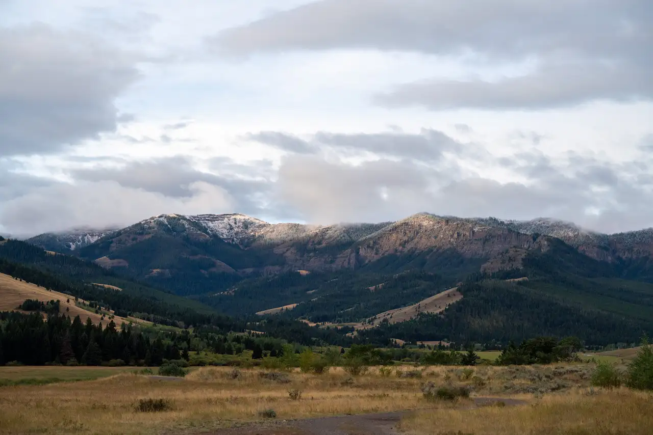 A mountain range with snow on top and a valley in the foreground