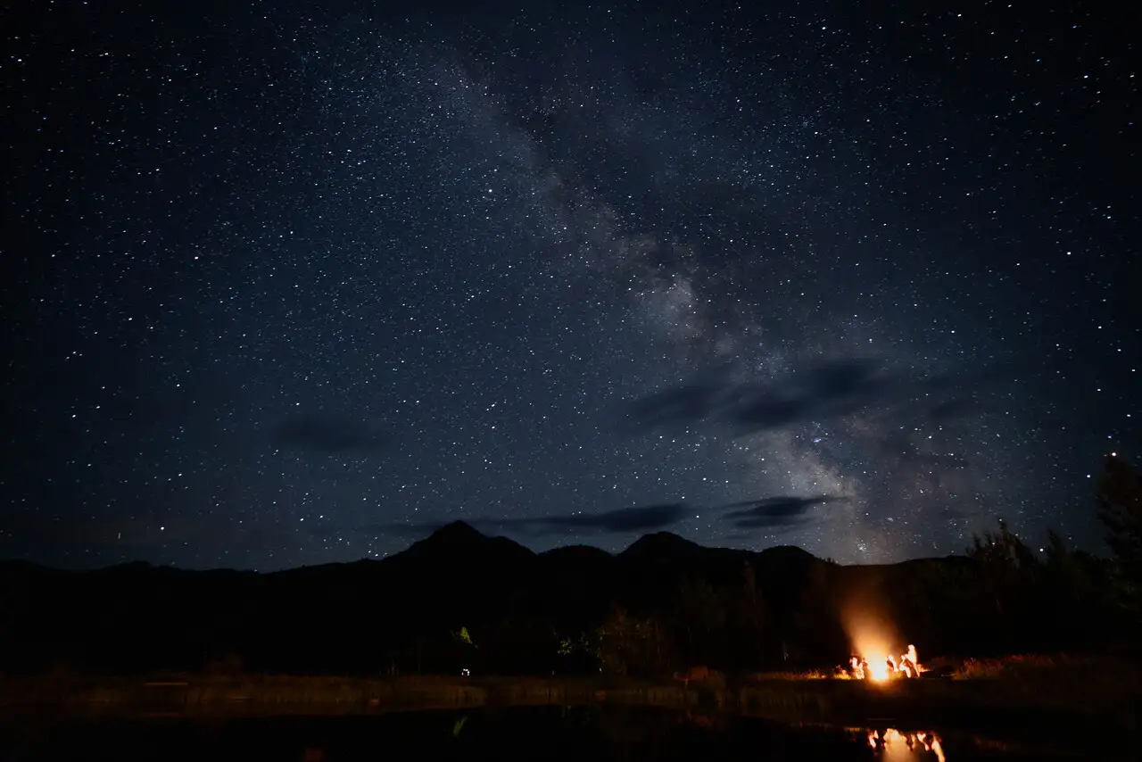 A nighttime scene with a meteor shower and a campfire