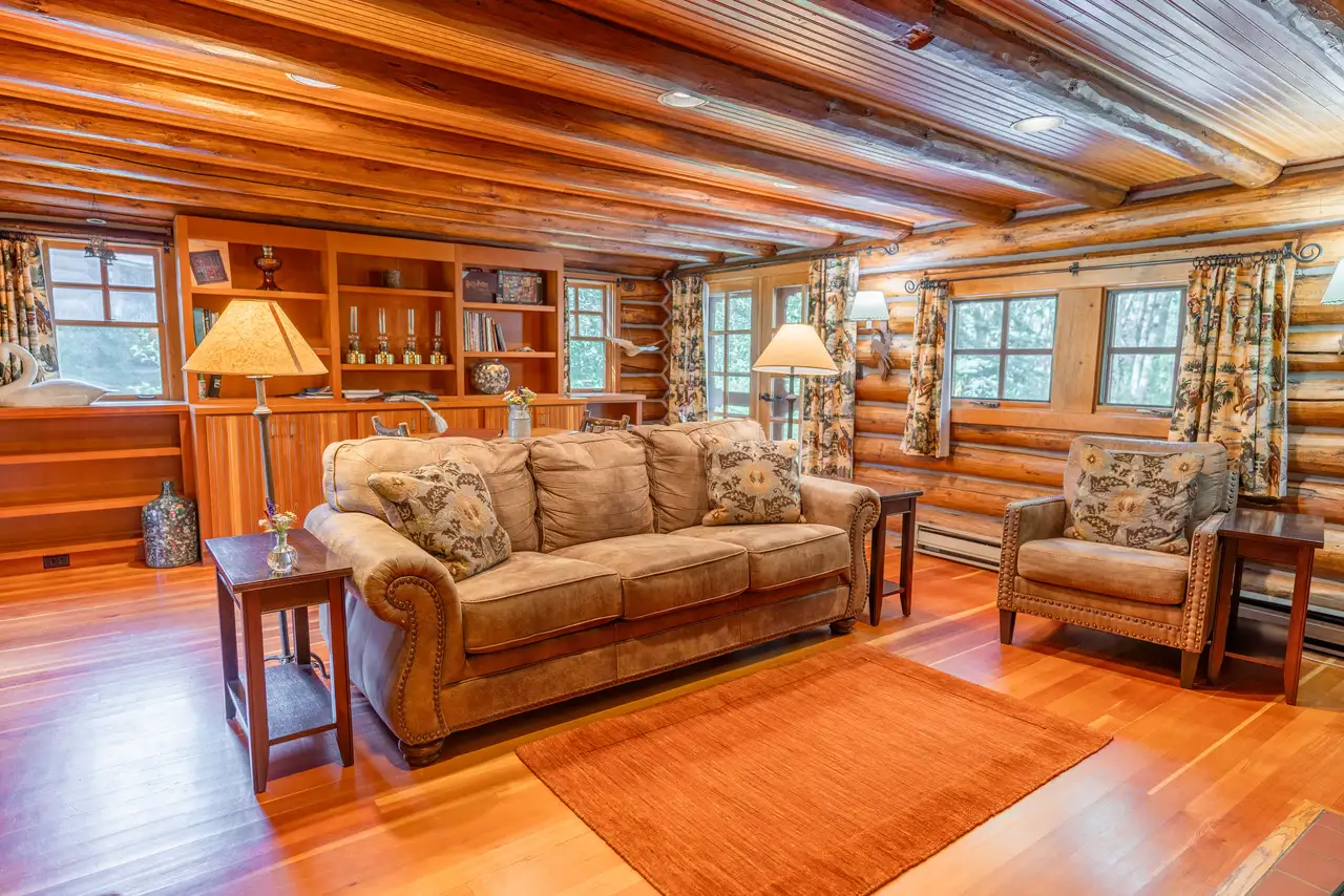 A living room with a brown couch, chair, lamp, and bookshelf