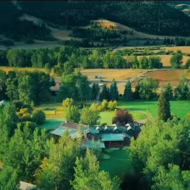 large house on a hill with a green roof and a green field surrounding it