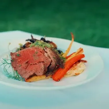 A plate of food with meat and carrots on a white plate