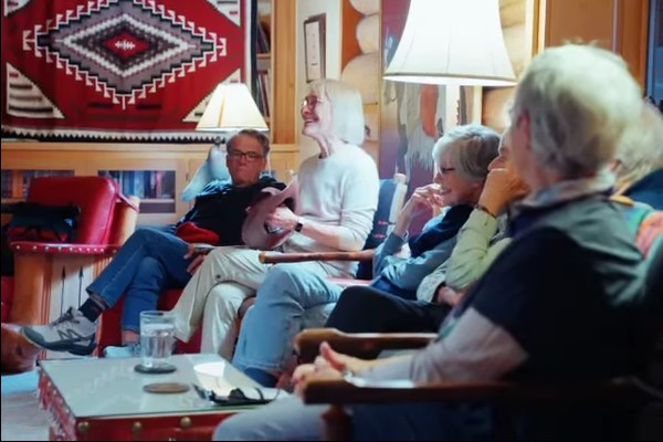 A group of people sitting in a living room, laughing and enjoying each other's company