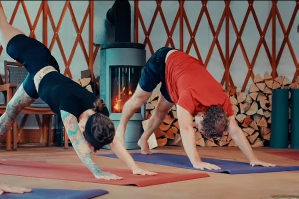 Two people doing yoga in front of a fireplace