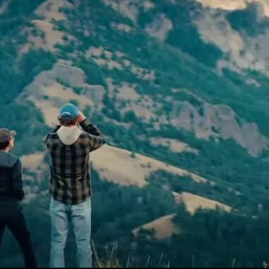 Two men on a hill looking at mountains