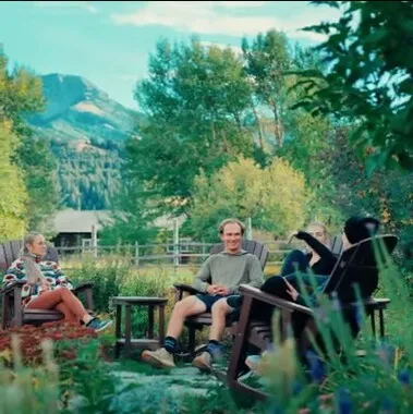 A group of people sitting in chairs in a garden, enjoying each other's company and the outdoors