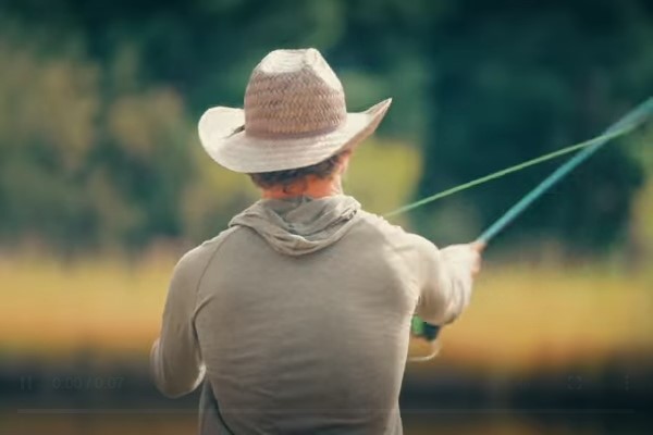 A man in a cowboy hat fishing in a river