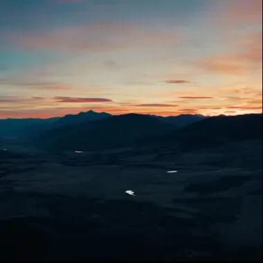 A mountain range at sunset with a blue sky and clouds