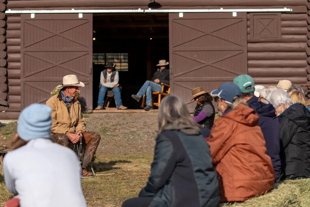 A group of people sitting outside a barn