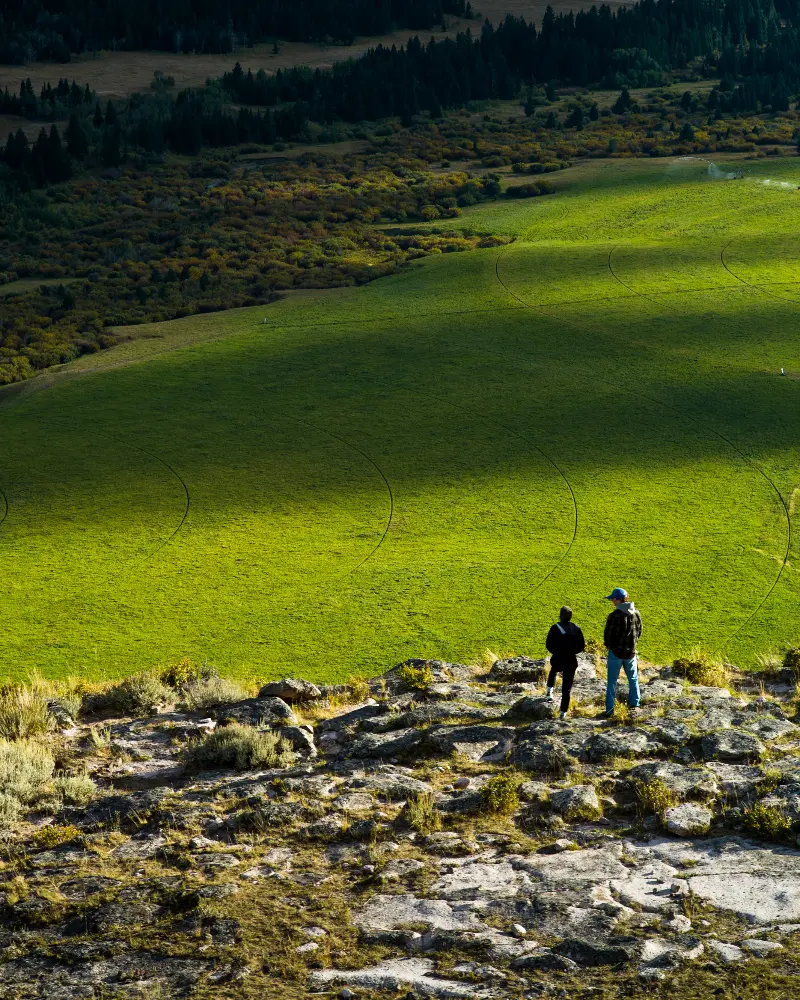 Two people standing on a hill overlooking a valley