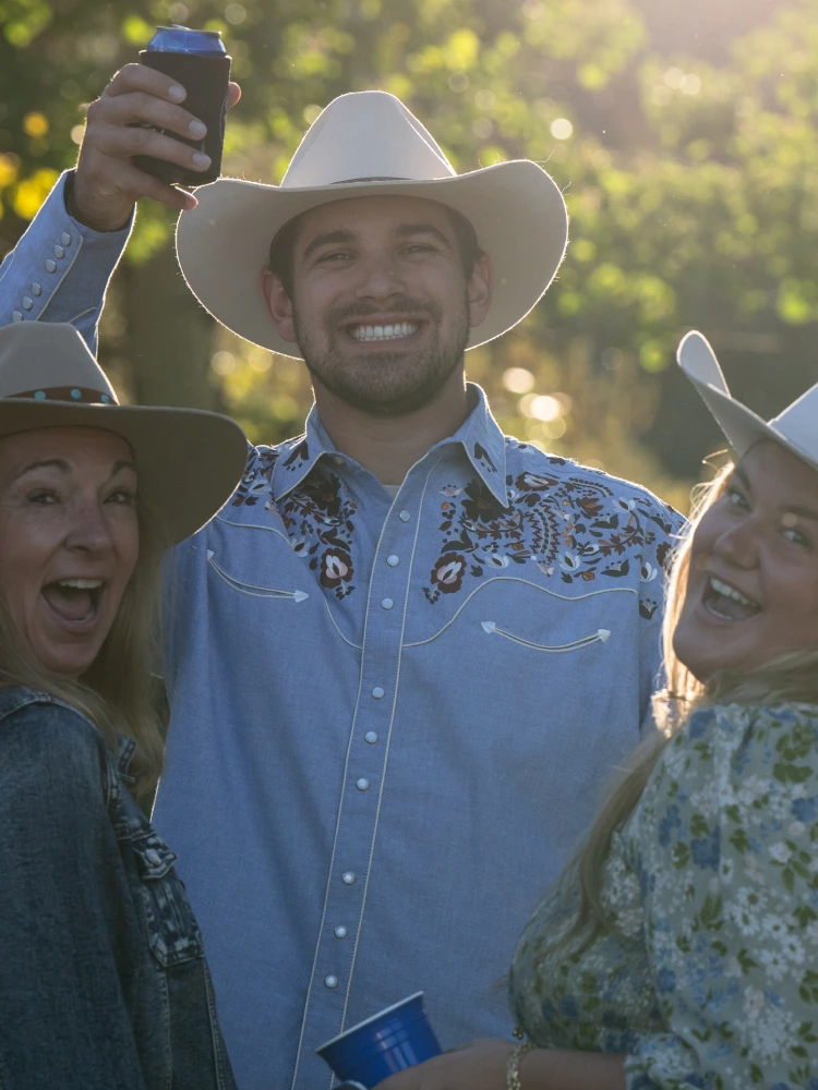 Three people wearing cowboy hats and smiling