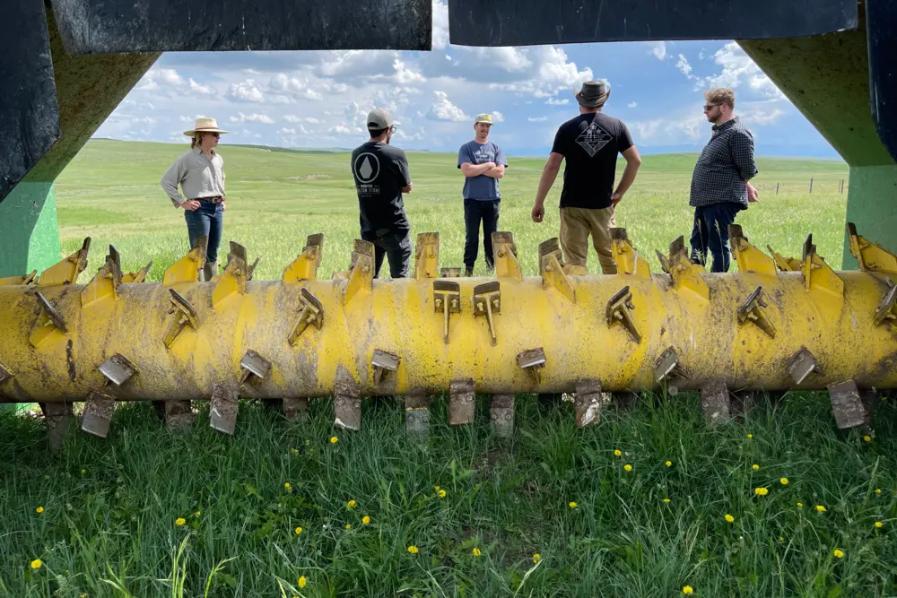 A group of people standing in front of a large yellow object with many handles