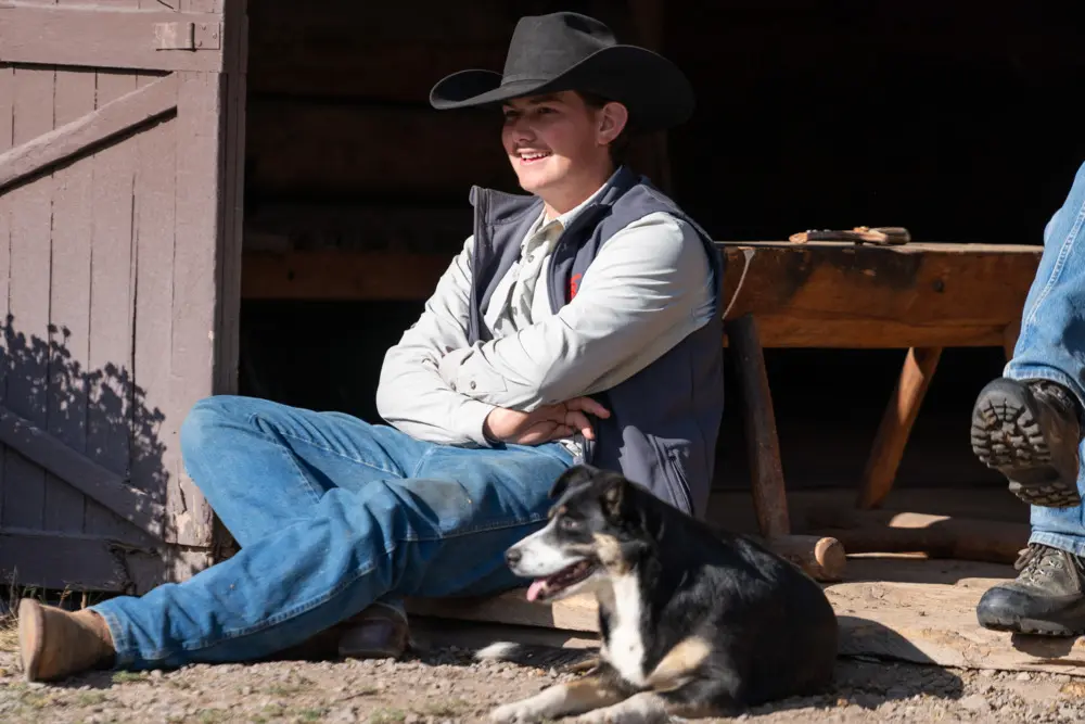 A man and his dog sitting on a bench outside