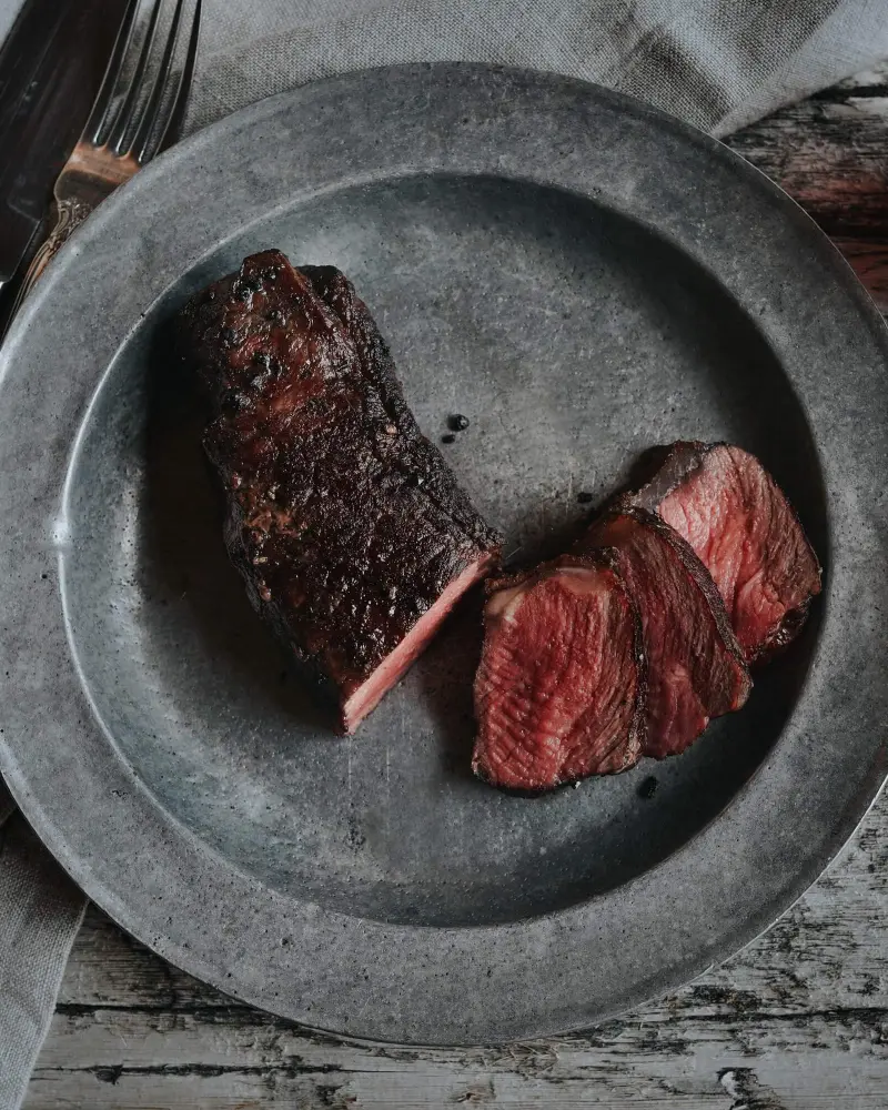 A piece of rare steak on a metal plate