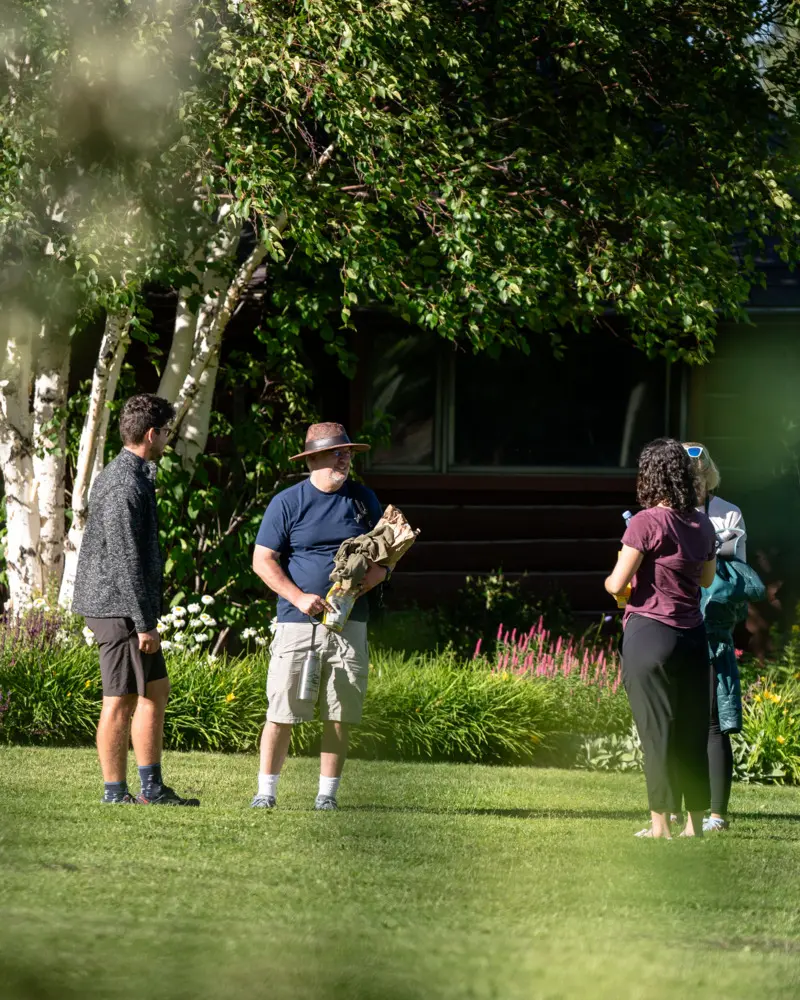 A group of people standing in a yard with a man holding a frisbee