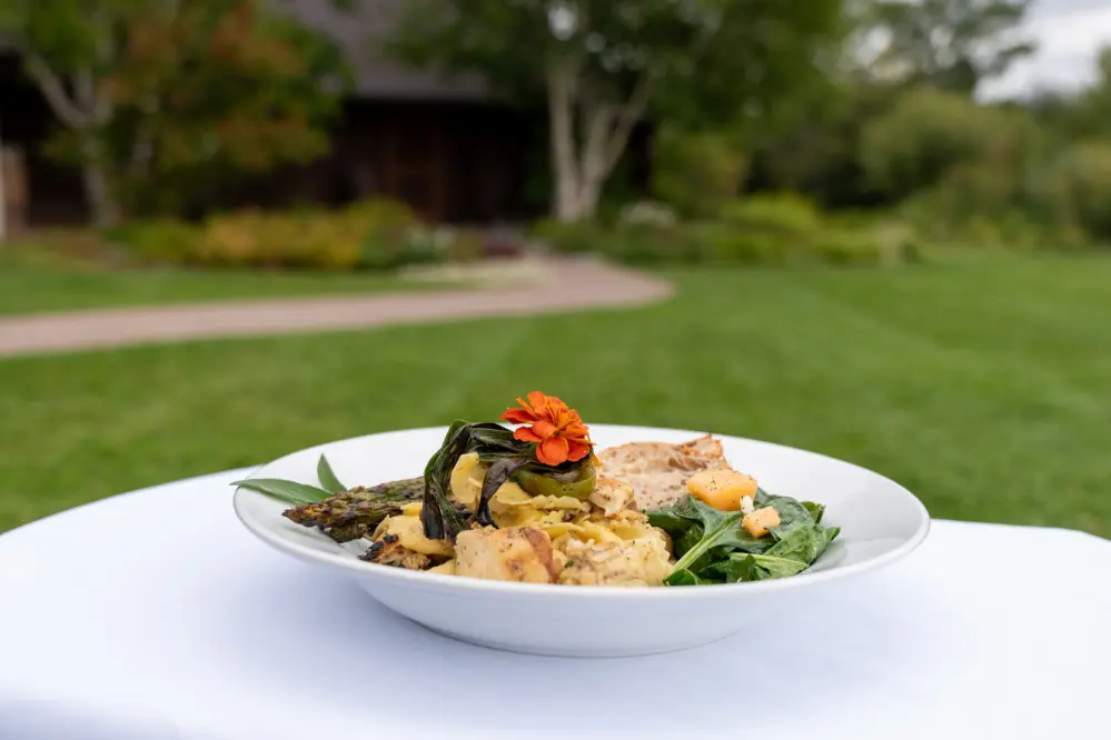 A bowl of food with a flower in the center, placed on a table outdoors