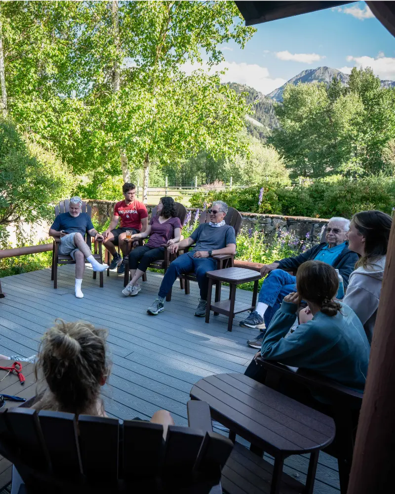 A group of people sitting on chairs on a deck, enjoying each other's company and the outdoors