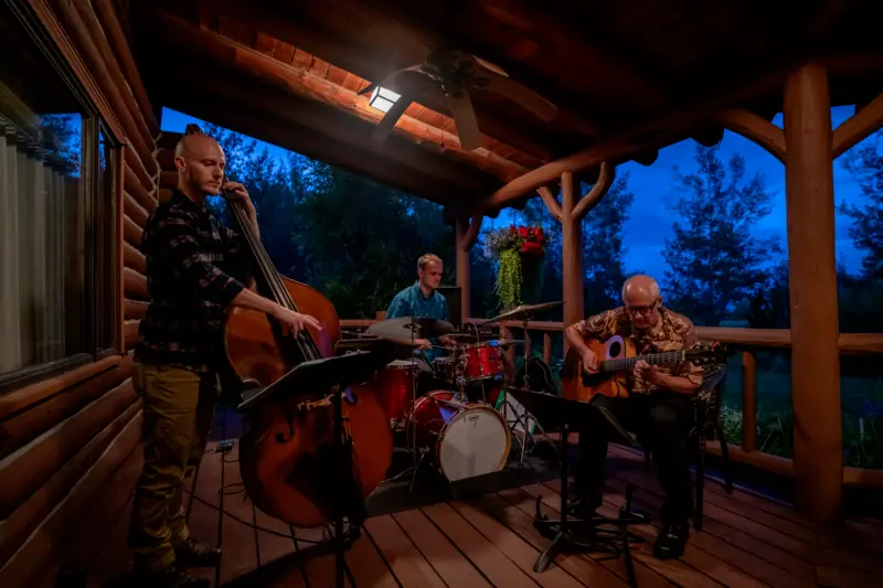 Three men playing music together on a porch