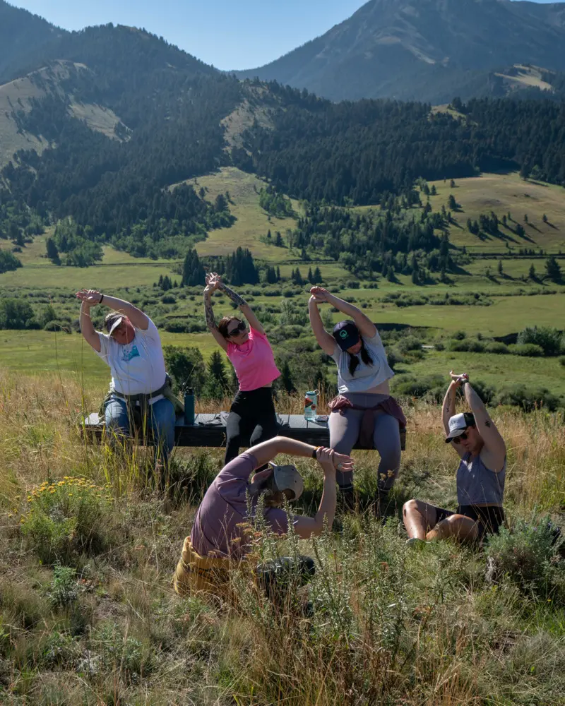 A group of people doing yoga on a hillside bench