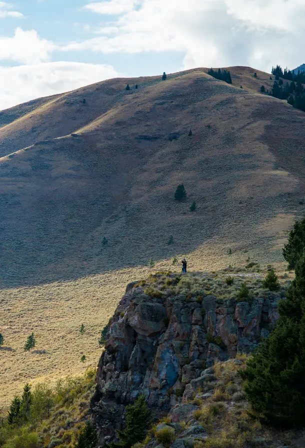 A man standing on a hillside looking out over the landscape