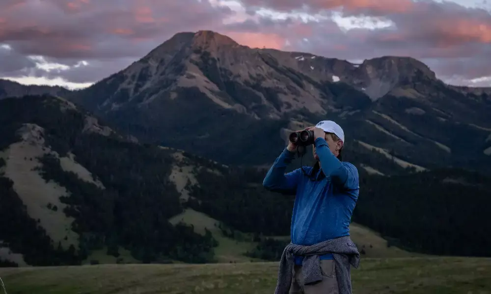 A man looking at mountains with binoculars