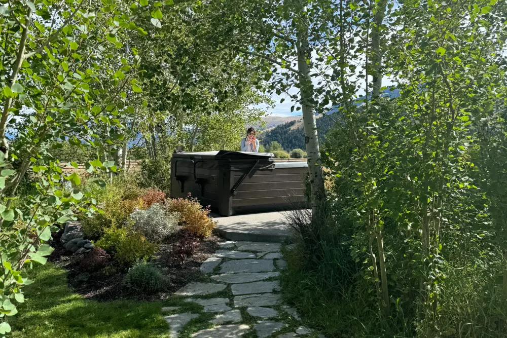 A woman sitting on a bench in a garden talking on her cell phone