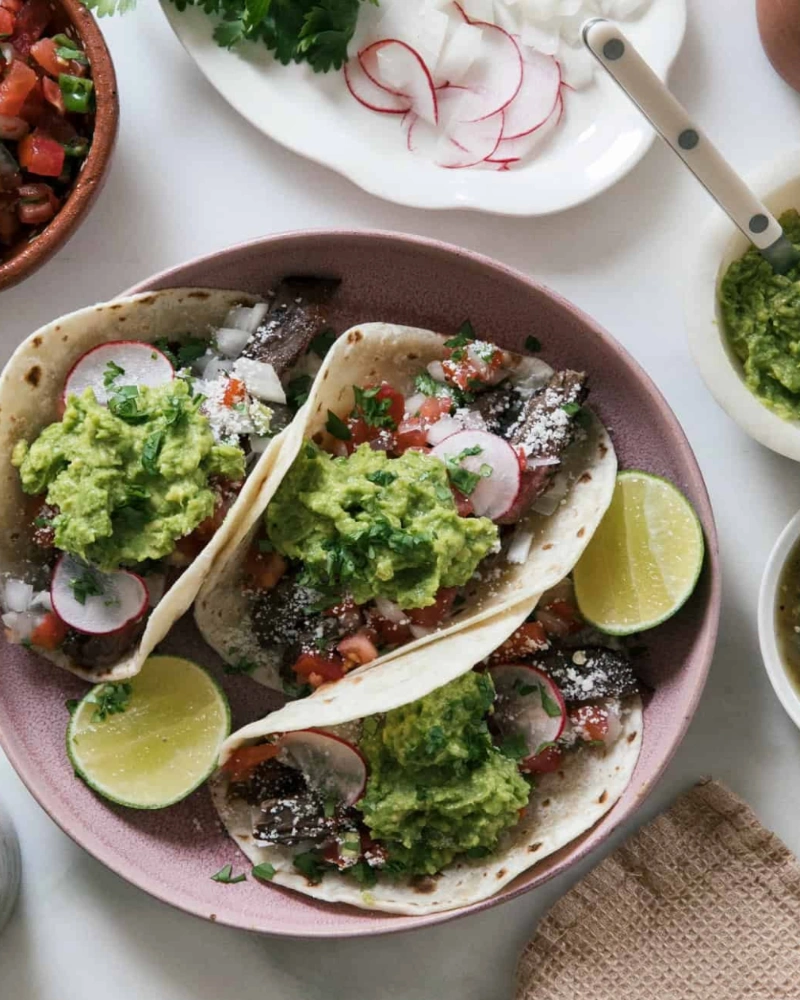 A plate of food with tacos, guacamole, and salsa