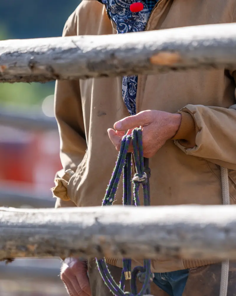 A man holding a rope in front of a wooden fence