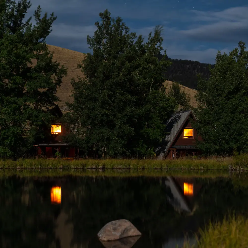 Two cabins by a lake at night