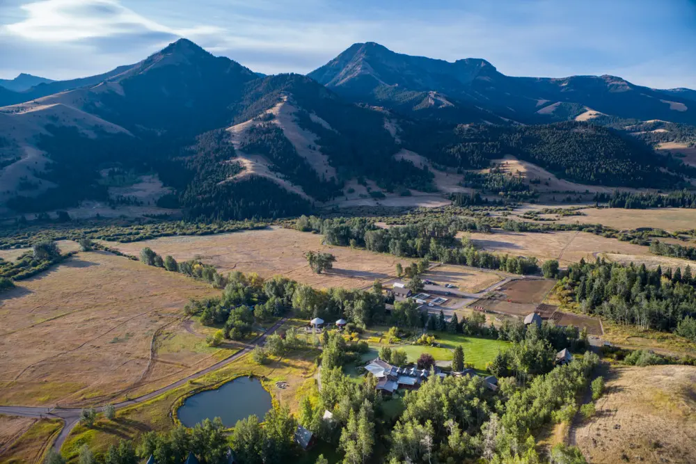 A valley with a lake and a house in front of mountains