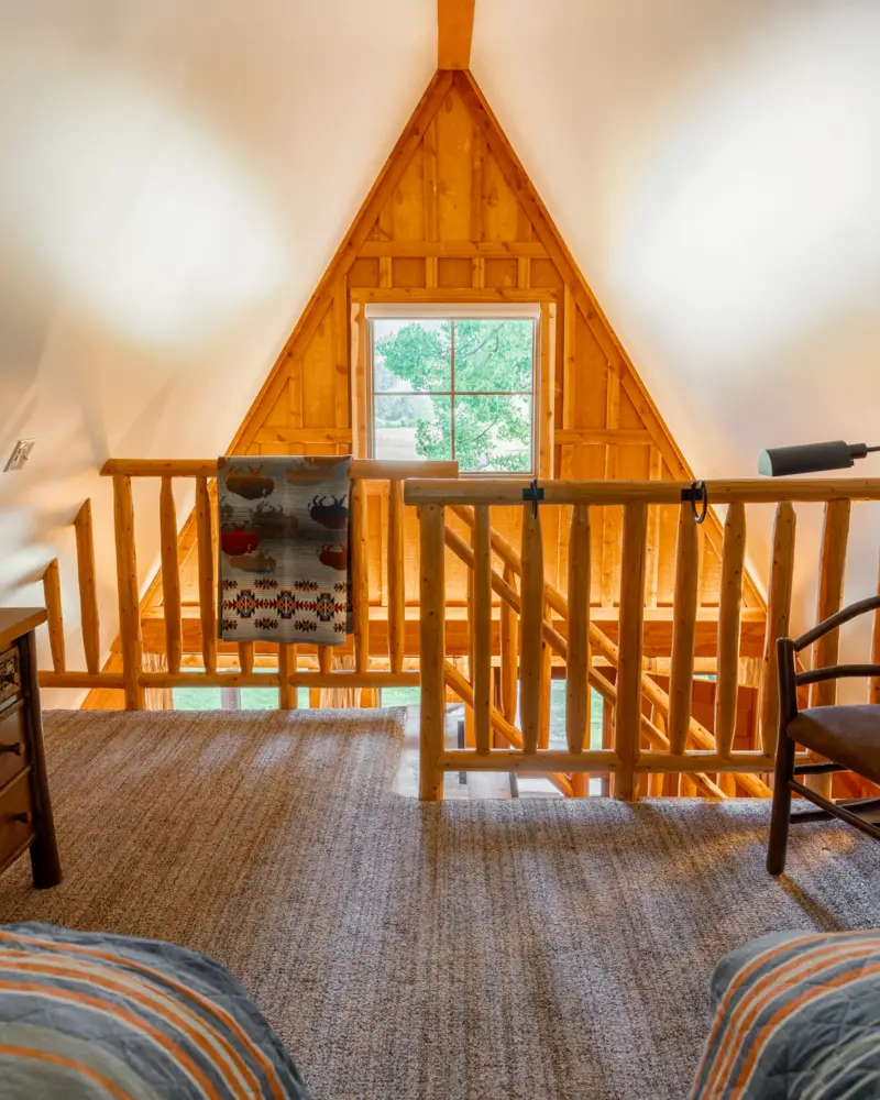 A wooden staircase with a railing and a window above it