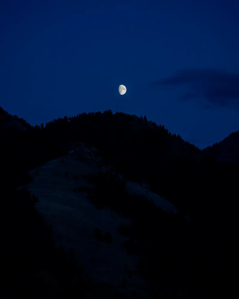 A full moon over a mountain range at night