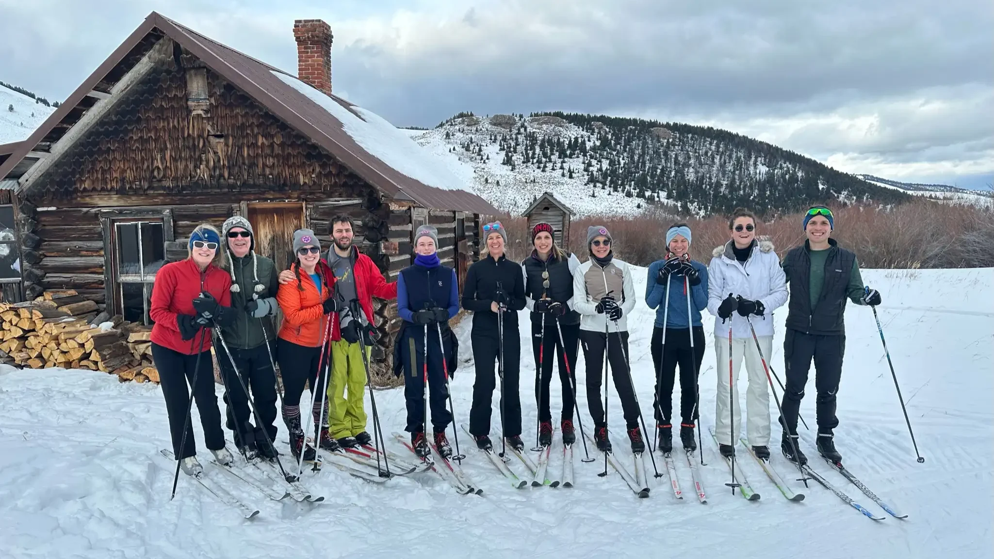 A group of skiers posing for a picture in front of a cabin