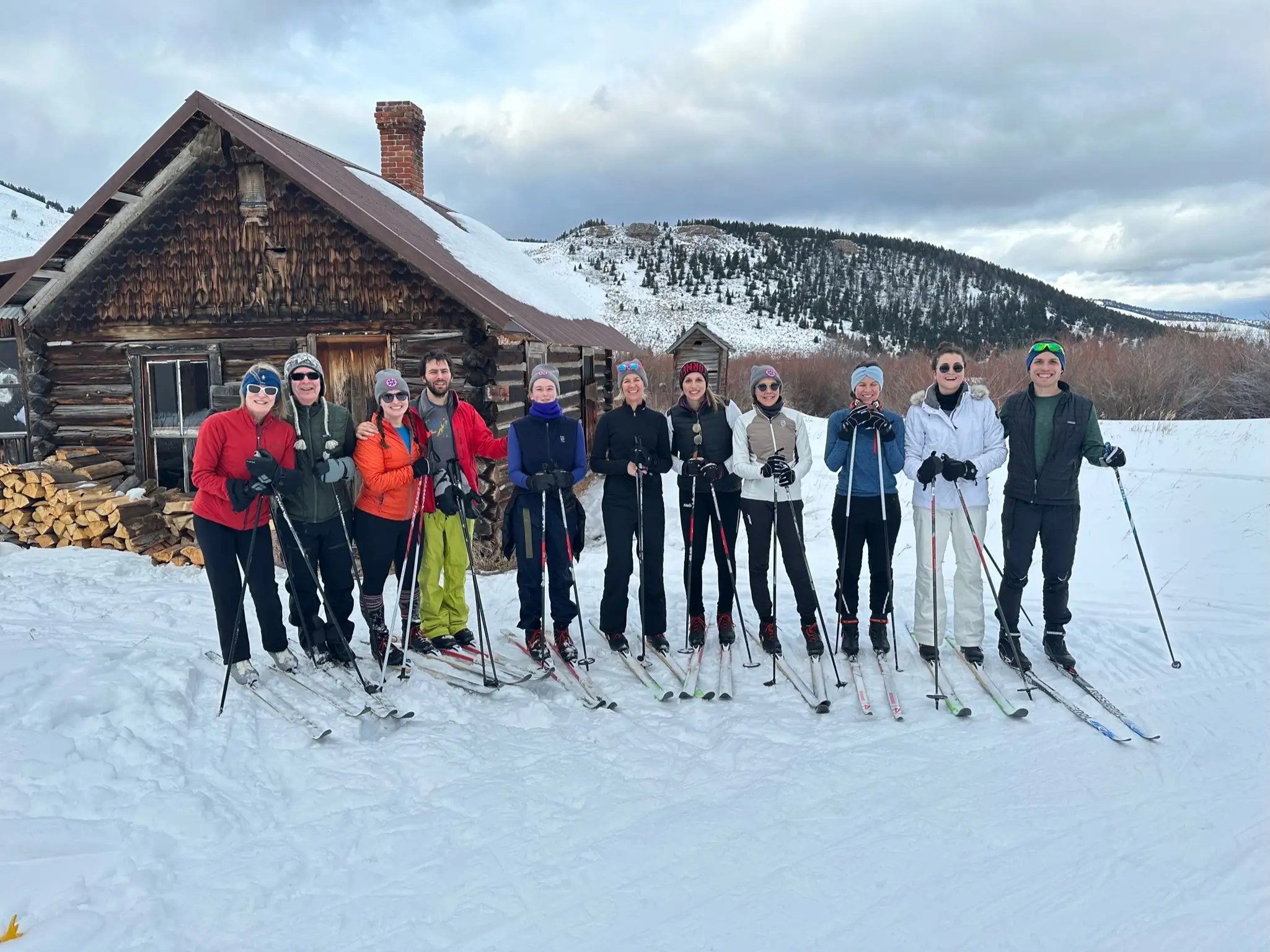 A group of skiers posing for a picture in front of a cabin